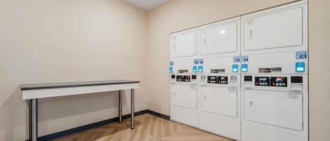 A laundry room with a table and multiple washing machines.