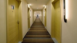 A hotel hallway with yellow walls, a striped carpet, and doors on both sides. - Yingdong Motel (Shanghai)