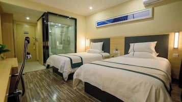 A hotel room with two beds, a wooden floor, a glass shower enclosure, and a mounted air conditioner.