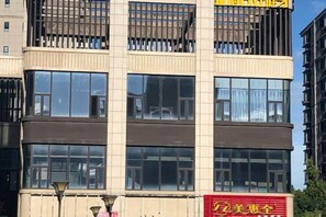 A multi-story building with large windows and a visible sign with yellow and red text. - Yingdong Motel (Shanghai)