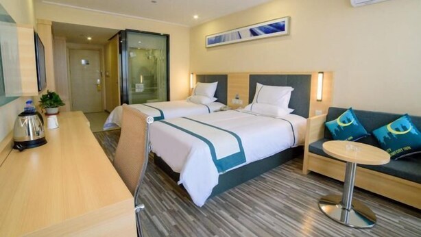 A hotel room with two beds, a desk, a small round table, and a sofa. - Yingdong Motel (Shanghai)