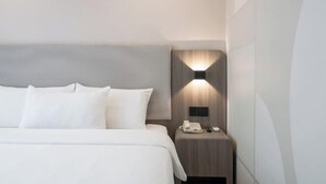 A hotel room with a bed, a bedside table with a phone, and a wall-mounted light fixture. - HanTing Hotel (Qinhuangdao Development Zone Yanshan University) (Qinhuangdao)