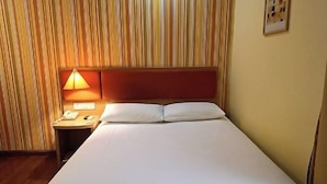 A hotel room with a bed, a nightstand with a lamp, and a striped wall. - Homeinn Hotel (Shanghai Pudong Xinchang Industrial Park Tanzhi Town) (Shanghai)