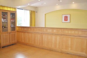 Una zona de recepción con un mostrador de madera, un armario de cristal y un cuadro en la pared.