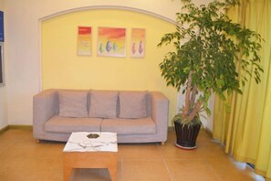 Una sala de estar con sofá, una mesa de centro y una planta en maceta.