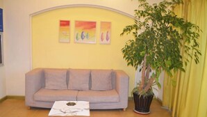 A living room with a grey sofa, a wooden coffee table, and a potted plant. - Homeinn Hotel (Shanghai Pudong Xinchang Industrial Park Tanzhi Town) (Shanghai)
