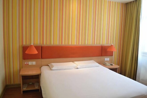 A hotel room with a striped wall, a bed with white linens, two orange lamps, a wooden nightstand, and a telephone. - Homeinn Hotel (Shanghai Pudong Xinchang Industrial Park Tanzhi Town) (Shanghai)