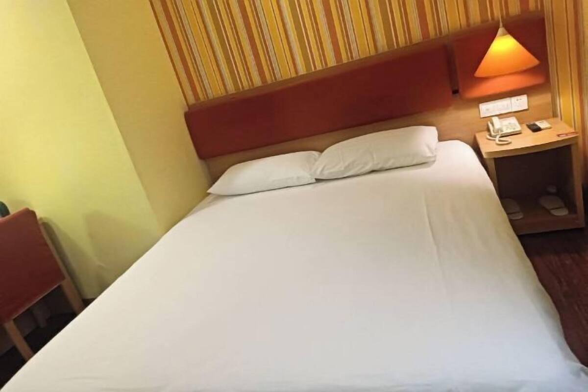 Ein Hotelzimmer mit Bett, Nachttisch und Lampe.