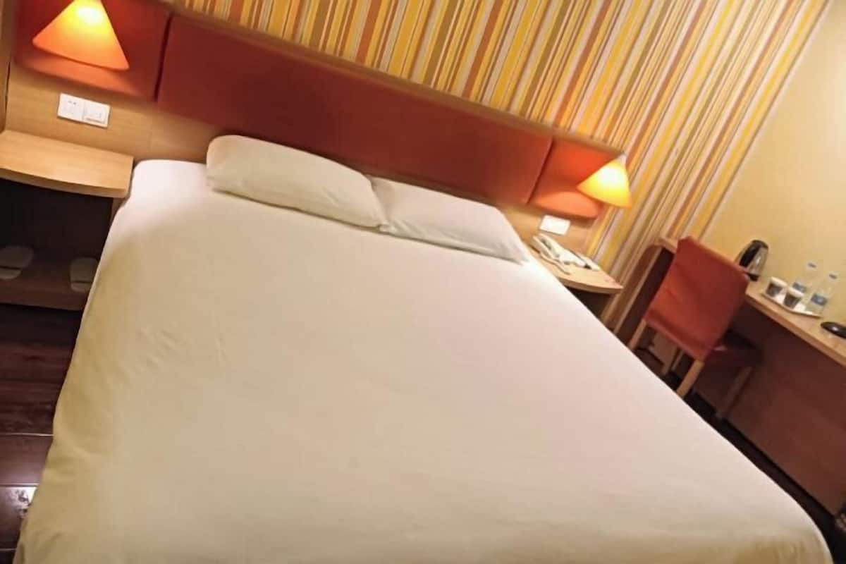 Ein Hotelzimmer mit Bett, Nachttischlampen, einem Schreibtisch und einem Stuhl.