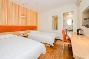 Une chambre d’hôtel avec deux lits, un bureau en bois, une chaise, un miroir et une fenêtre.
