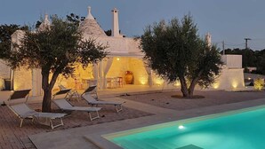 A villa with a swimming pool, outdoor seating, and a well-lit patio area. - Trullo Sogni Di Pietra - Ostuni (Ostuni)