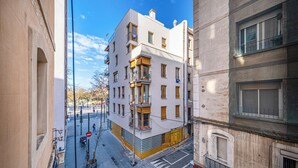 Un edificio de varios pisos con fachada moderna, ventanas grandes y un balcón visible en el segundo nivel.