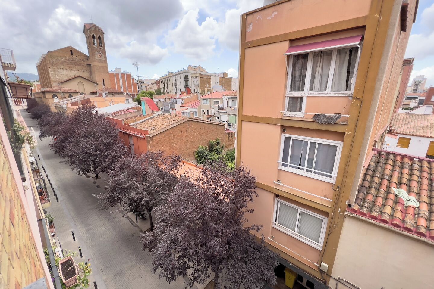 A street view with buildings, a church, and trees.