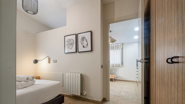 A modern bedroom with a bed, bedside lamp, and two framed artworks on the wall. - Bebarceloner Sants Estudios A5 (Barcelona)