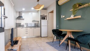 A modern kitchen with white cabinets, a microwave, and a refrigerator. There is a dining area with a round table and two chairs. - Bebarceloner Sants Estudios A5 (Barcelona)