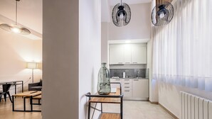 A modern kitchen with white cabinets, a wooden table, and a hanging light fixture. - Bebarceloner Sants Estudios A6 (Barcelona)