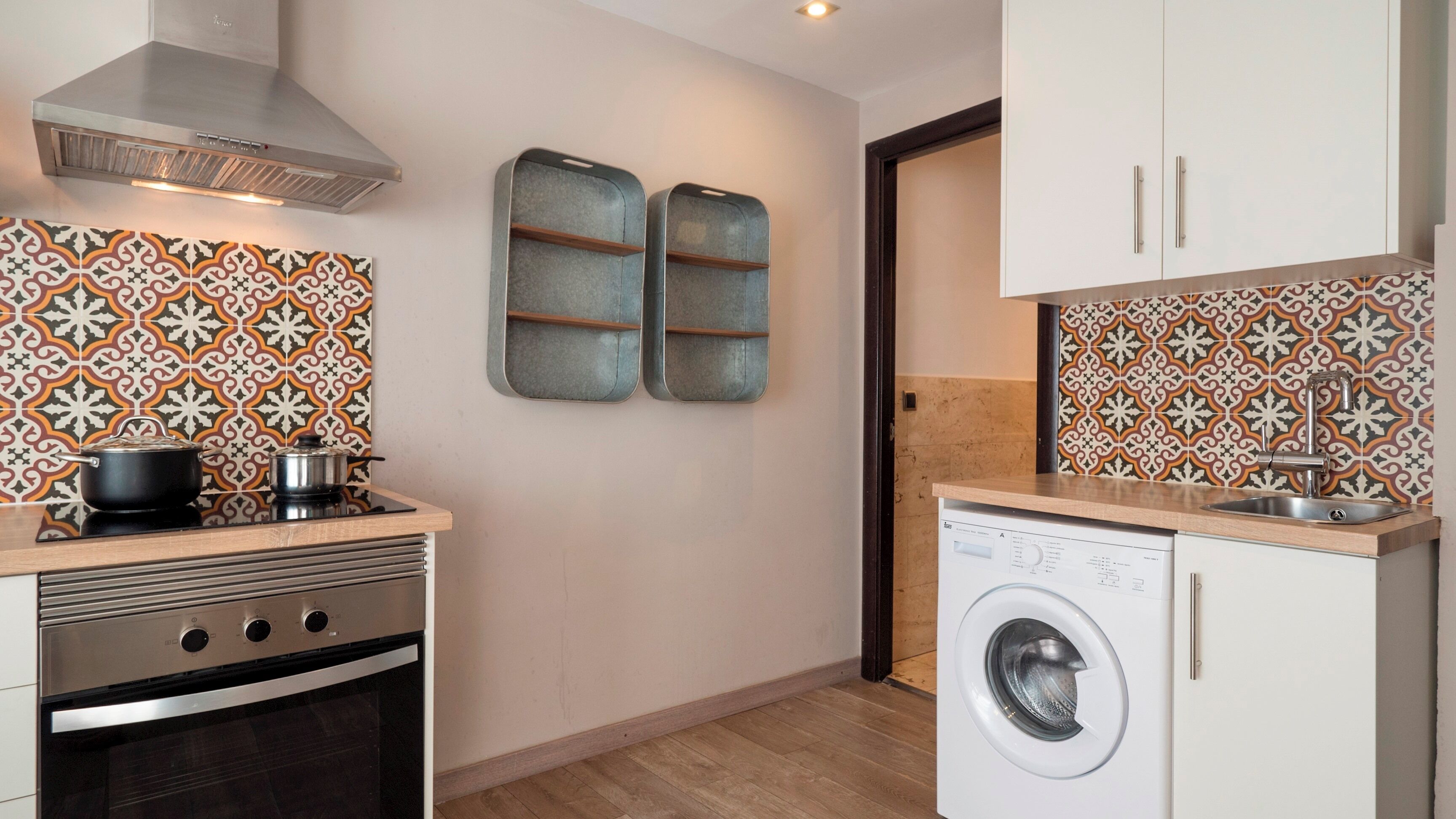 A compact kitchen with a stove, oven, microwave, and a washing machine.
