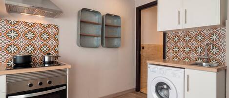 A compact kitchen with a stove, oven, microwave, and a washing machine.