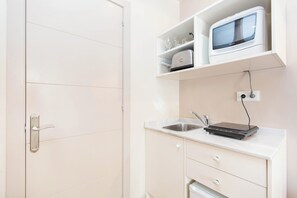 A compact kitchenette with a microwave, a sink, and a countertop.