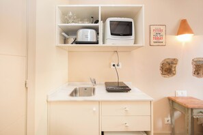 A compact kitchen with a microwave, toaster, and a small table. - BeBarceloner Gothic Estudios (Barcelona)