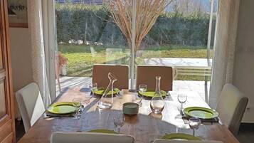 Un coin repas avec une table dressée pour quatre personnes, de grandes fenêtres et une vue sur l’extérieur.