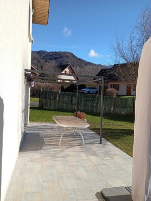A patio with a table and chairs, a car parked in the background, and a mountain in the distance. - 🏡 House with mountain view and garden - between Annecy and Val d'Arly resorts  (Ugine)