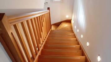 Un escalier en bois, doté d’une rampe, mène à un palier où se trouve une petite fenêtre.