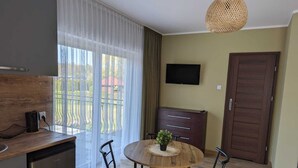 Een kleine keuken met een eethoek, een televisie en een deur.