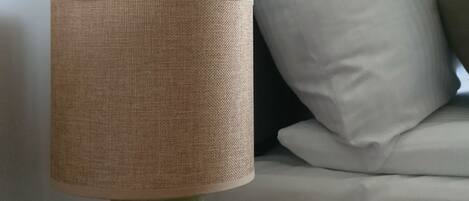 A green table lamp with a woven shade on a wooden nightstand.