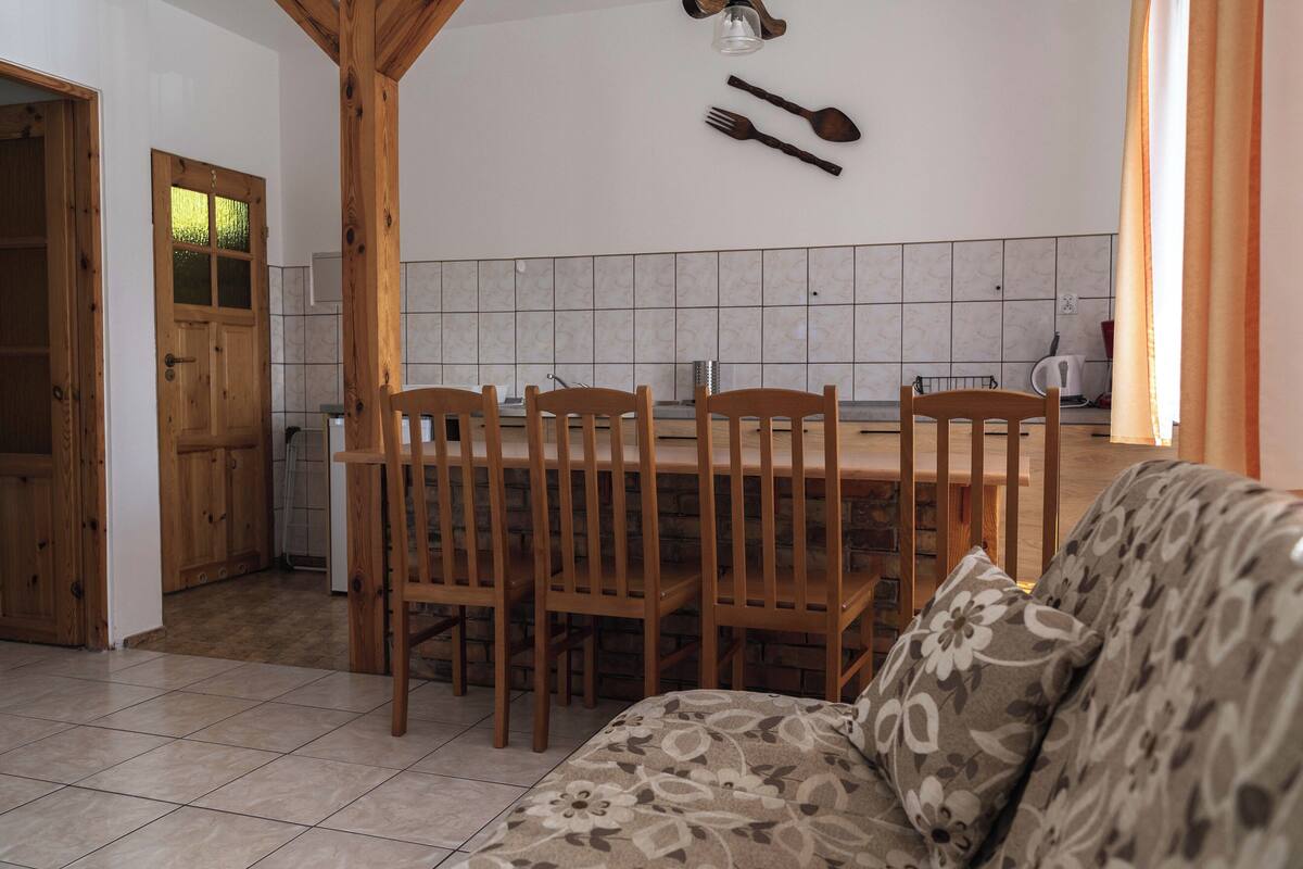 A dining area with a wooden table and chairs, a tiled backsplash, and a wooden door.