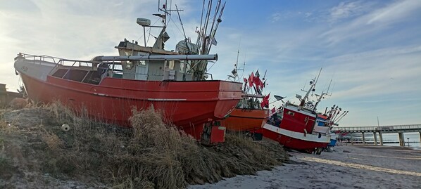 Two boats docked at a pier with a bridge in the background.