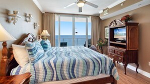 Une chambre d’hôtel avec un lit, un ventilateur de plafond, une télévision et une vue sur l’océan.