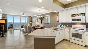 Une cuisine spacieuse avec des meubles blancs, un grand îlot central et une vue sur l’extérieur.