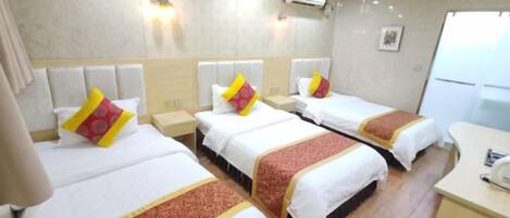 A hotel room with three beds, a desk, and a bathroom.