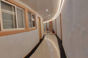 A hotel corridor with a polished floor, doors on the left, and a red object in the distance. - Wanlike Business Hotel Chengdu Chunxi (Chengdu)