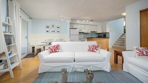 Ein modernes Wohnzimmer mit einem weißen Sofa, einem Glastisch und Holzböden.