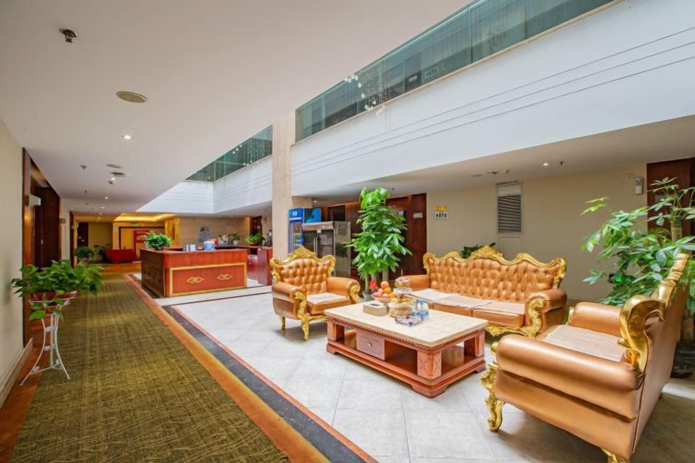 A spacious lobby with a reception desk, seating area with sofas, and a central coffee table.