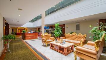 A spacious lobby with a reception desk, seating area with sofas, and a central coffee table.