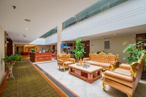 A spacious lobby with a reception desk, seating area with sofas, and a central coffee table. - M Hotel (Dongguan Haichao) (Dongguan)