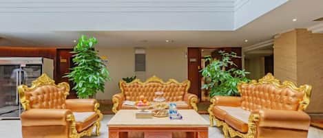 A luxurious living room with ornate golden furniture, a central coffee table, and large potted plants.