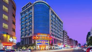 A hotel with a curved facade, multiple floors, and illuminated signage.