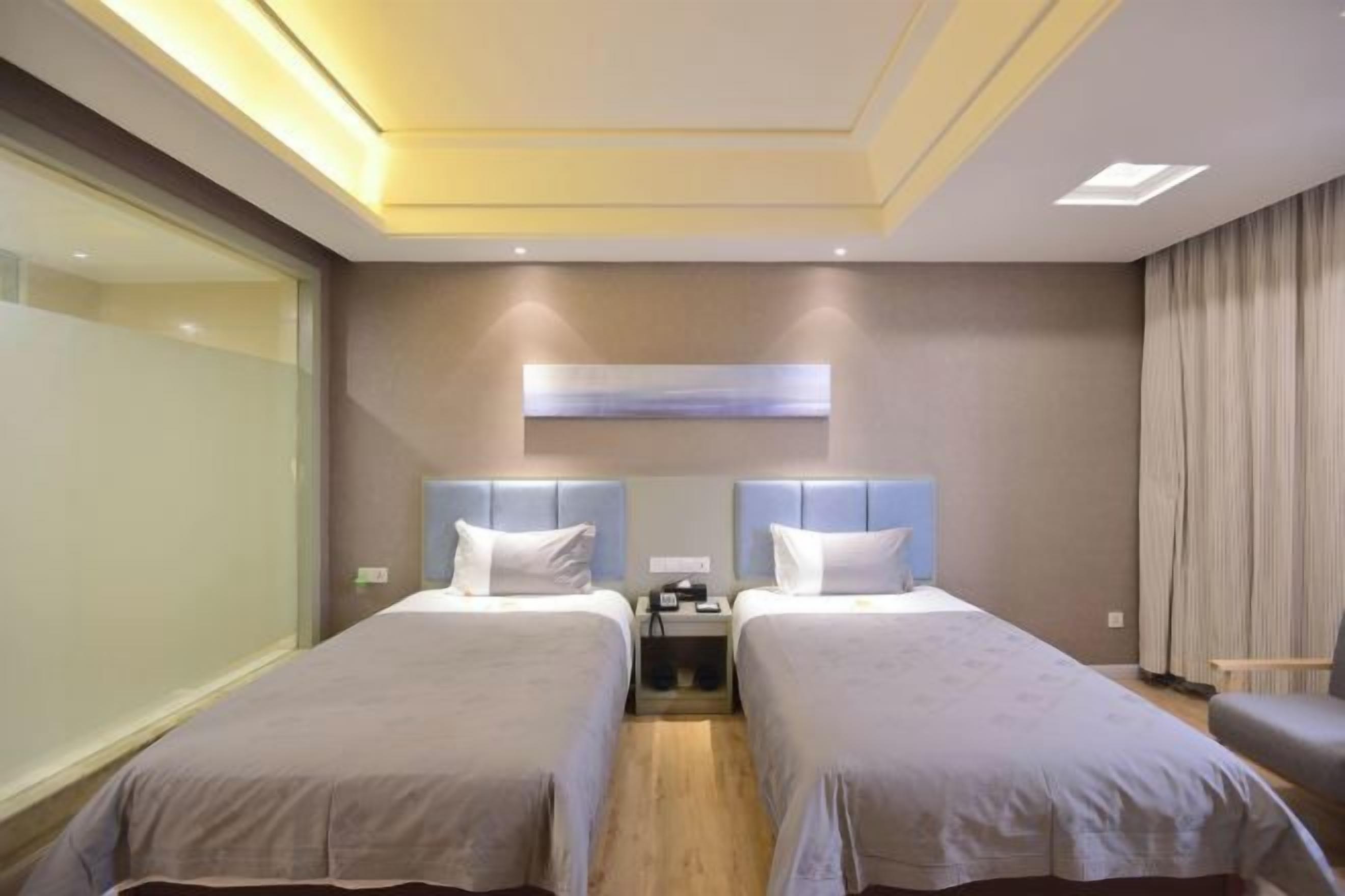 A hotel room with two beds, a desk, and a chair.