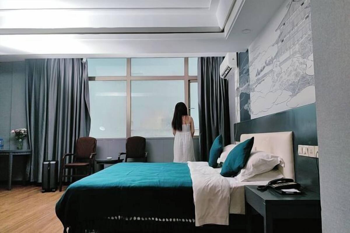 Habitación de hotel con cama, escritorio, silla, ventana y pared con un mapa.