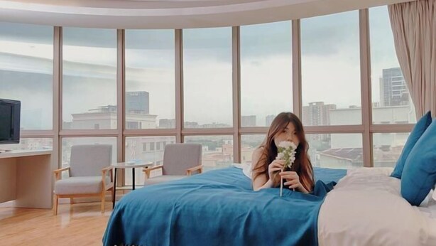 A bedroom with a large window, a bed, a desk, and a chair. - M Hotel (Dongguan Haichao) (Dongguan)