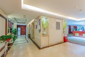 A hotel lobby with a reception desk, potted plants, and a fire extinguisher. - M Hotel (Dongguan Haichao) (Dongguan)
