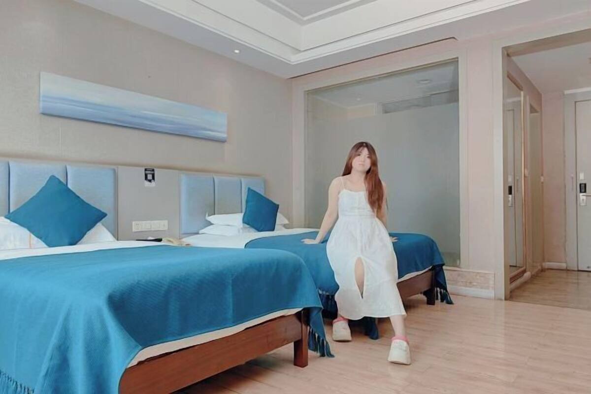 Habitación de hotel con dos camas, un espejo grande y una puerta corredera que da a otra habitación.