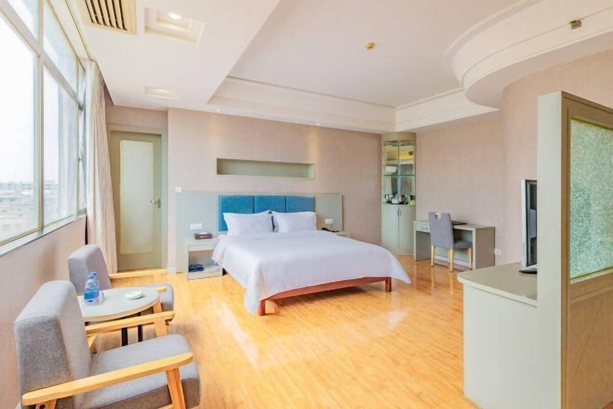 Una habitación de hotel con cama, escritorio, silla, televisor y ventana.