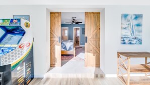 A room with a bed, a ceiling fan, wooden doors, a painting, and a table. - Pool & Waterfront! Tiki Hut+Close To Beach! (Pompano Beach)