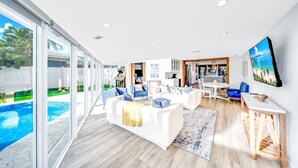 A spacious living area with a pool view, modern furniture, and a kitchen area. - Pool & Waterfront! Tiki Hut+Close To Beach! (Pompano Beach)