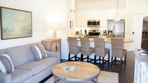 A modern kitchen with white cabinets, stainless steel appliances, and a dining area with wicker chairs.
